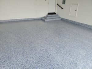 Epoxy garage floor including coating the foundation walls in a white, gray and blue fleck.