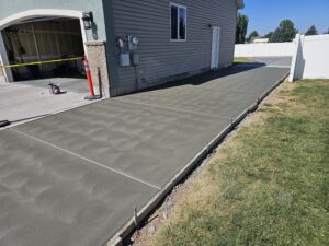New concrete RV pad running the length of the driveway and the house. Care has been taken not to damage the white vinyl fence.