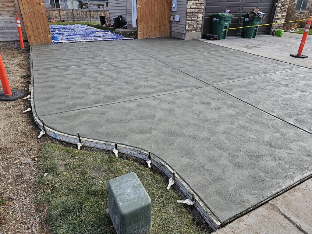 New concrete driveway with curved edges and sweat finished surface.
