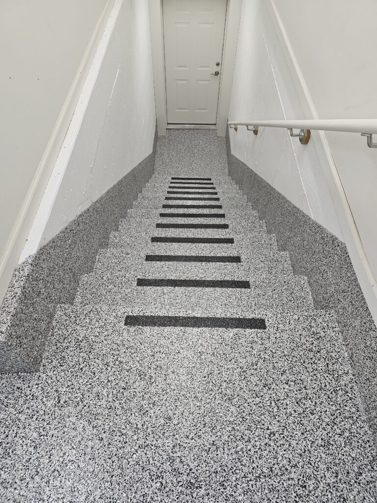 epoxy coated stairs leading to a basement with black edging.