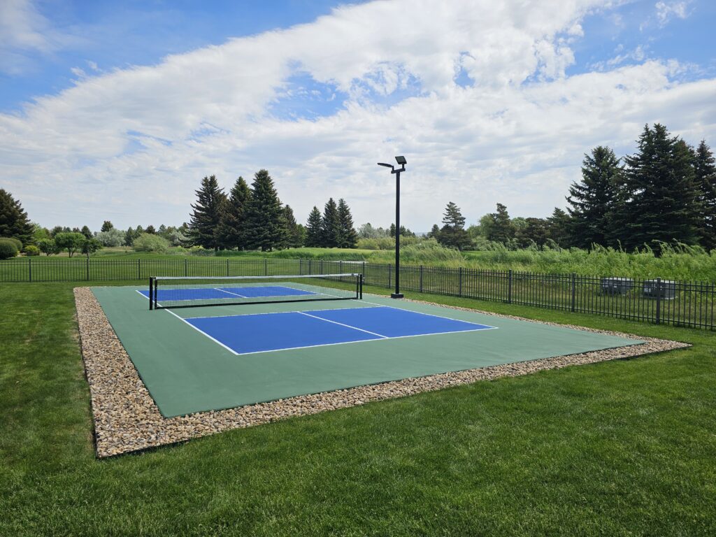 Residential pickleball court installed with lighting and finished landscaping.