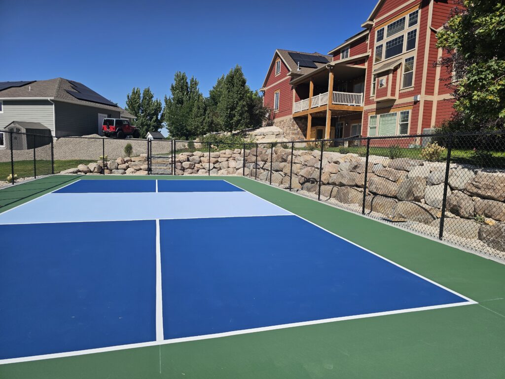 post tension concrete sports court set on a backyard hillside with fencing and landscaping.