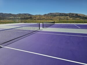 New high school tennis courts with installed tennis net posts and nets and new USTA white lines.